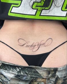 a woman's stomach with the words lucky you tattooed on her lower back side