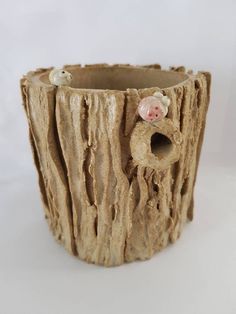 a wooden vase with two little pigs sticking out of it's holes in the bark