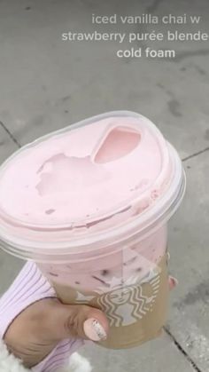 a person holding up a cup with pink liquid on it's side and the words iced vanilla chai water strawberry puree blended cold foam