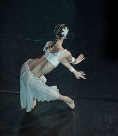 a ballerina in white is performing on the floor with her arms outstretched and legs spread out