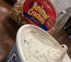 an ice cream in a cup next to a bag of crackers on a table