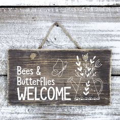 a wooden sign hanging on the side of a building that says bees and butterflies welcome