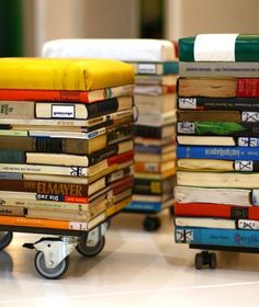 several stacks of books are stacked on top of each other and sitting on small wheels