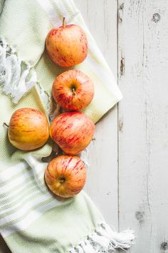 four apples sitting on top of a green and white towel next to an apple slice