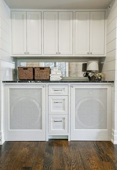 a kitchen with white cabinets and wood flooring on the walls, along with two wicker baskets