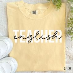 a t - shirt with the word english written on it next to sneakers and flowers