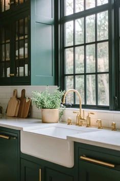 a kitchen with green cabinets and white counter tops, gold faucets and wooden cutting boards