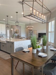 a kitchen and dining room with an island in the middle, lights hanging from the ceiling