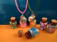 four small bottles are sitting next to each other on a table with two necklaces hanging from them