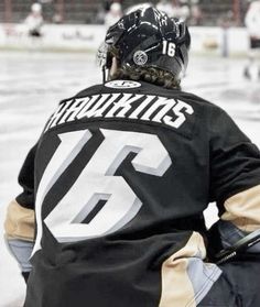 a hockey player sitting on the ice with his back to the goalie's net