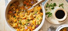 a bowl filled with rice and vegetables on top of a table next to two plates