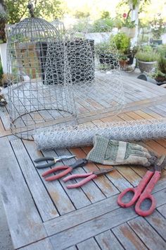 some tools are laying out on a wooden table outside in front of a birdcage