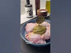 a blue bowl filled with chicken and seasoning on top of a counter