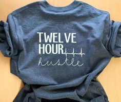 a t - shirt with the words twelve hour hustle on it sitting on top of a wooden table