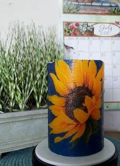 a sunflower painted on the side of a blue and white cup sitting on top of a table