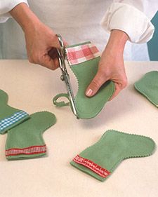 a person cutting fabric with scissors on top of a white table and some green mitts