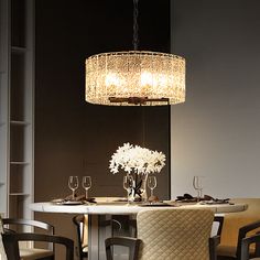 a chandelier hanging over a dining room table with wine glasses and flowers on it