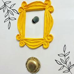 a yellow frame with a button on it sitting next to a drawing of leaves and branches