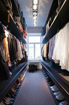 an image of a walk in closet with shoes on the floor and clothes hanging up