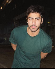 a man in a green t - shirt posing for the camera