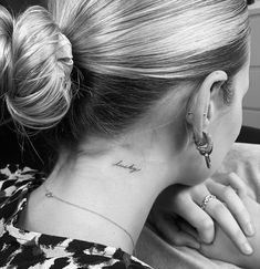 a woman with a tattoo on her neck and behind her ear is looking at the camera