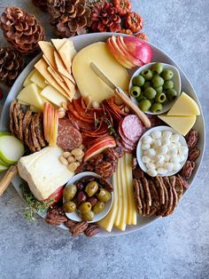 a platter filled with cheese, crackers, olives, and other snacks