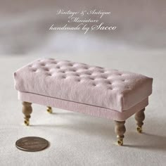 a small pink bench sitting on top of a white table next to a dime coin