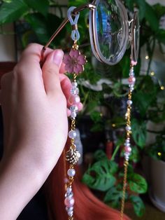 a person is holding some beads near a potted plant and a pair of glasses