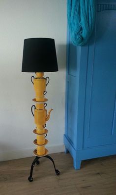 a yellow lamp sitting on top of a wooden table next to a blue cabinet with a black shade