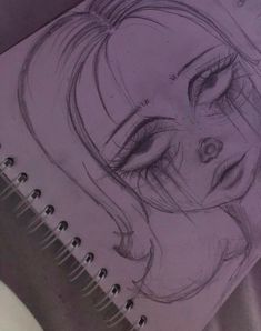 a drawing of a woman's face on top of a spiral notebook with pencil