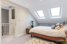 a bed sitting under two windows in a bedroom next to a white door and window