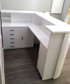 an office desk with white drawers and cabinets