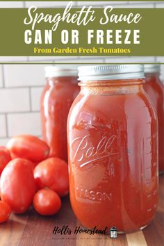 two jars filled with tomato sauce sitting on top of a wooden table next to tomatoes