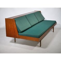 a green couch sitting on top of a white floor next to a wooden frame and headboard