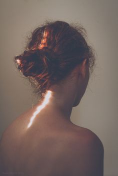 the back of a woman's head with sun shining on her shoulder and shoulders