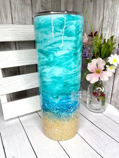 a blue vase sitting on top of a wooden table next to a vase filled with flowers