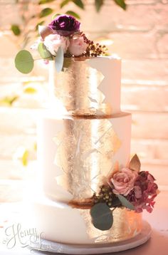 a three tiered wedding cake with flowers on top