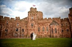 a bride and groom standing in front of a castle