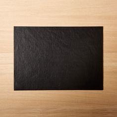 a black square shaped piece of leather on top of a wooden surface