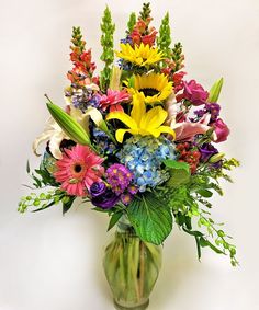 a vase filled with lots of different colored flowers