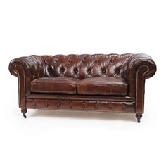 a brown leather couch sitting on top of a white floor