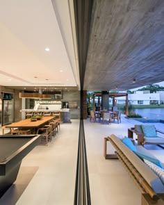 a pool table in the middle of a large open living room with an outdoor kitchen and dining area