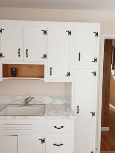 a kitchen with white cabinets and marble counter tops