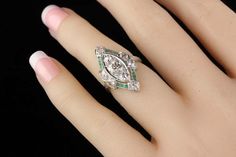 a woman's hand with a diamond and emerald ring on it