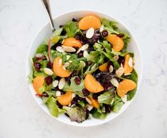 a white bowl filled with salad topped with oranges and almonds