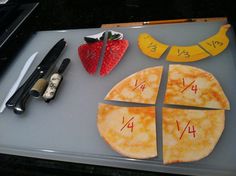 a cutting board with cut up pizzas and fruit on it next to knifes