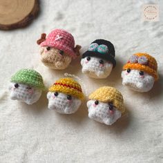 small crocheted toys are sitting on a white sheet next to a wood slice