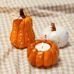 three small pumpkins sitting on top of a checkered cloth covered tablecloth next to each other