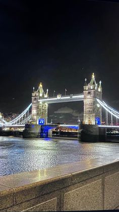 the tower bridge is lit up at night, with lights on it's sides