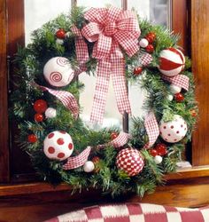 a christmas wreath with ornaments hanging on the front door and in front of a window